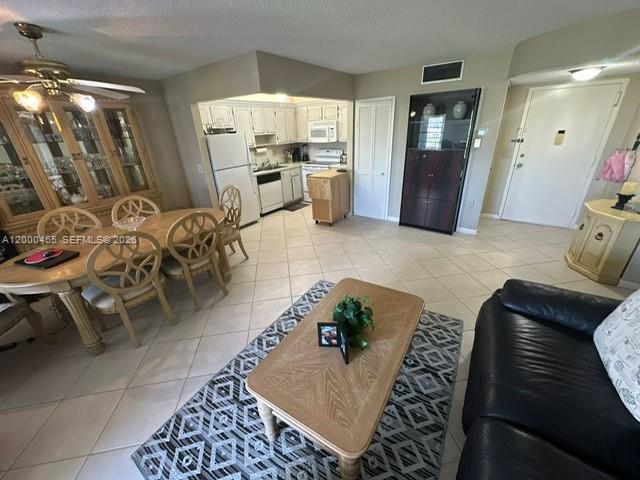 This open-concept living and dining area features tile flooring, a kitchen, and a ceiling fan — 4980 E Sabal Palm Blvd # 330, Tamarac FL 33319, TAMARAC, FL