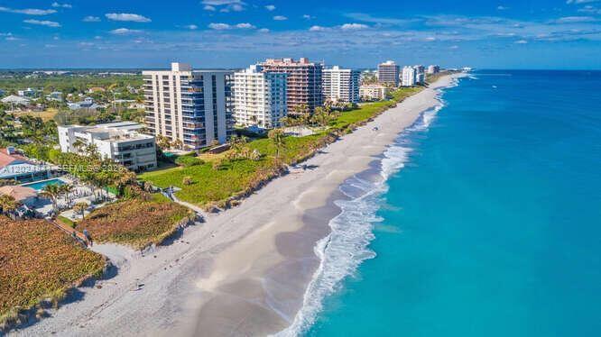 An aerial view of a sandy beach lined with high-rise apartment buildings and ocean water — 420 Celestial Way # 101, Juno Beach FL 33408, JUNO BEACH, FL