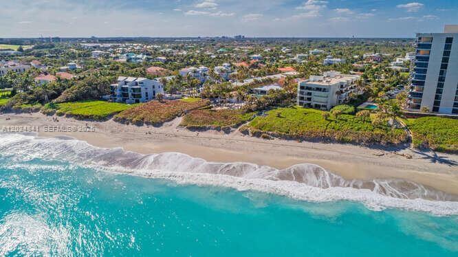 An aerial view of a sandy beach with ocean waves and several multi-story residential buildings — 420 Celestial Way # 101, Juno Beach FL 33408, JUNO BEACH, FL