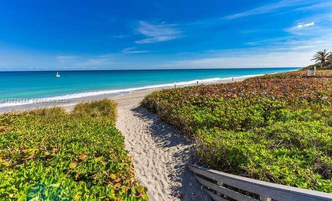 A sandy path leads through coastal vegetation to a beach with turquoise water — 420 Celestial Way # 101, Juno Beach FL 33408, JUNO BEACH, FL