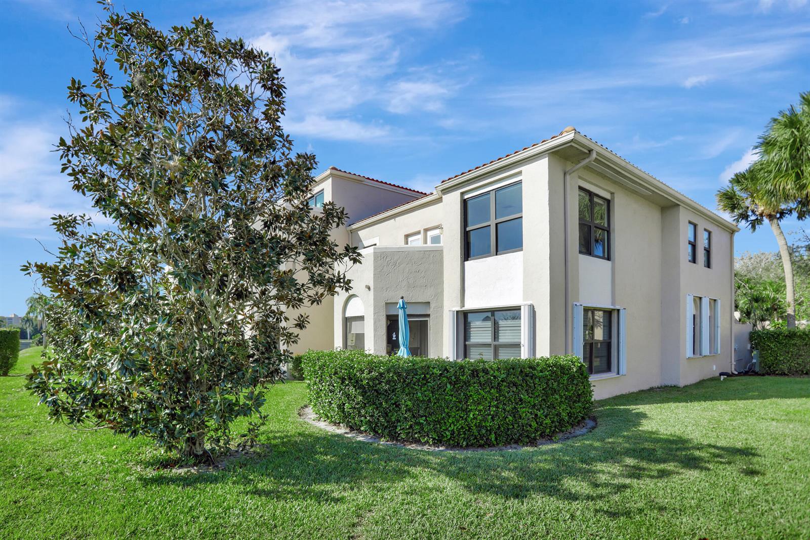 A two-story beige house features a manicured hedge, a large tree, and a grassy lawn — 6646 Villa Sonrisa Drive # 520, Boca Raton FL 33433, BOCA RATON, FL