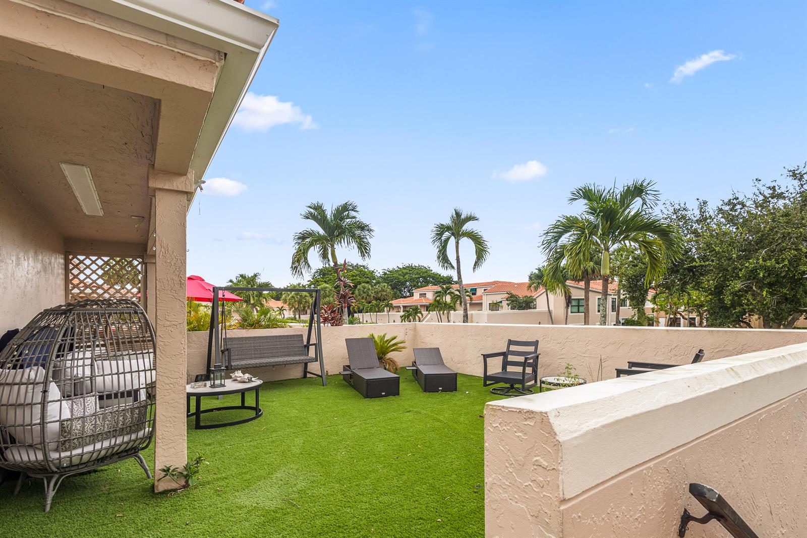 A patio with artificial turf, outdoor furniture, and a low wall under a blue sky — 6646 Villa Sonrisa Drive # 520, Boca Raton FL 33433, BOCA RATON, FL