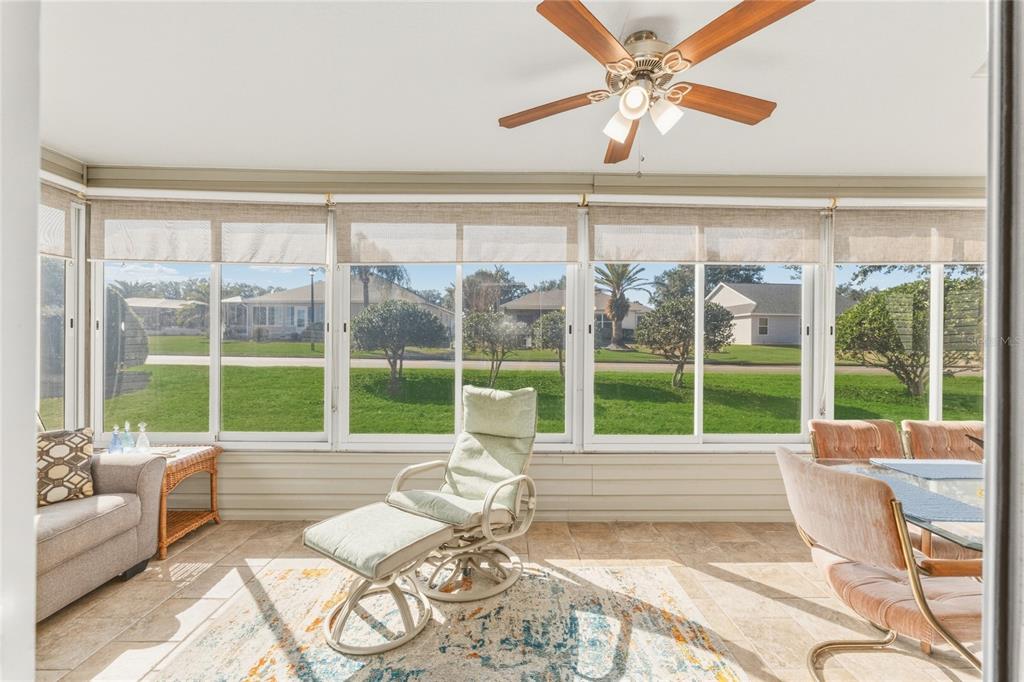 A sunroom with tile floors, a ceiling fan, and large windows overlooking a grassy yard — 8337 SE 176TH LAWSON LOOP, THE VILLAGES, FL