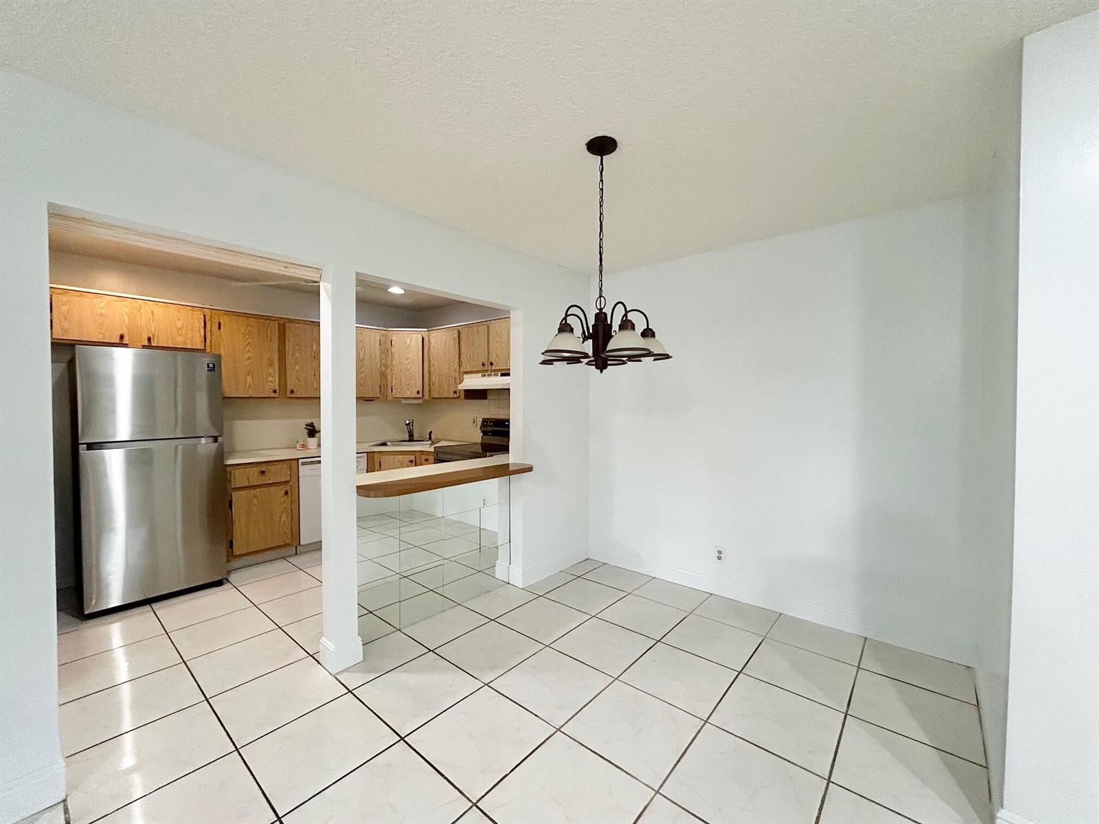 A dining area with tile floors and a chandelier opens to a kitchen with cabinets — 433 Pine Glen Lane # C2, FL 33463, FL