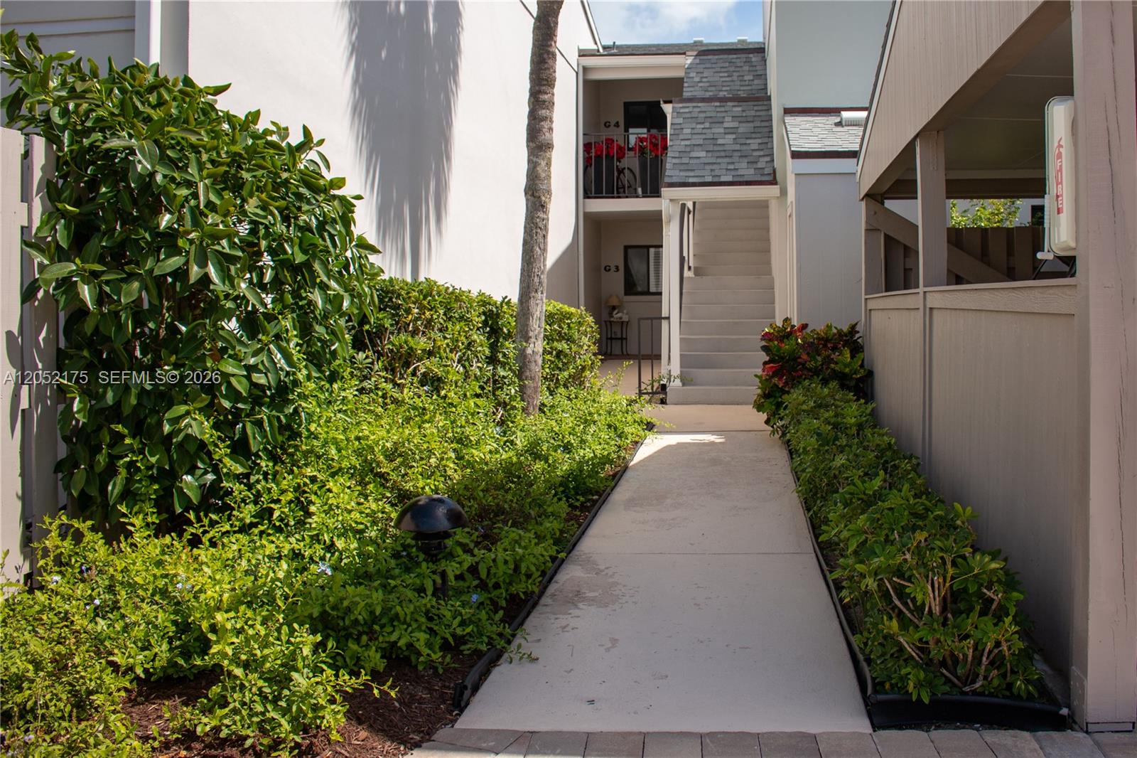 A concrete walkway leads to a staircase between two residential building units — VERO BEACH, FL
