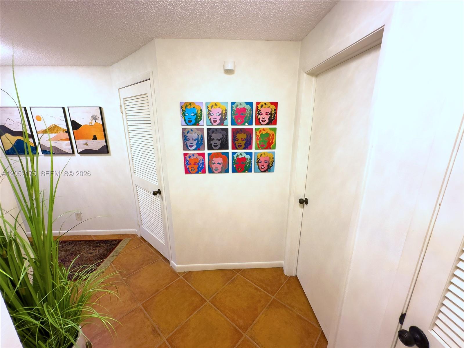 A hallway features tile flooring, white doors, and a wall display of Marilyn Monroe prints — VERO BEACH, FL