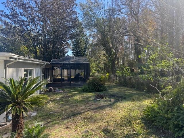 An empty bedroom features light-colored walls, wood-look flooring, two windows, and a ceiling light fixture — 7235 REDBUD COURT, NEW PORT RICHEY, FL