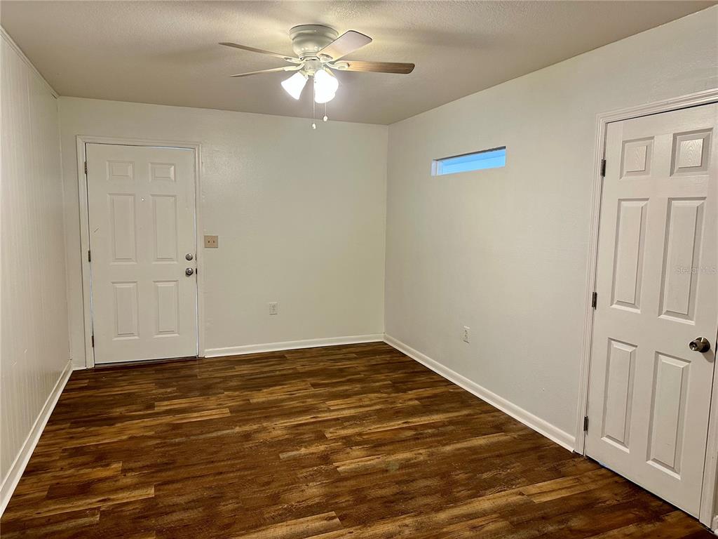 An interior room features wood-look flooring, white walls, a ceiling fan, and two white doors — 1103 CYPRESS GARDENS BOULEVARD UNIT 51, WINTER HAVEN, FL