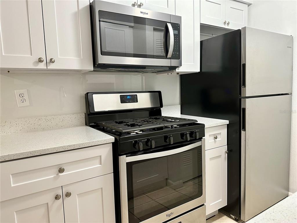 A kitchen features white cabinets, stainless steel appliances, and light-colored countertops — 1103 CYPRESS GARDENS BOULEVARD UNIT 51, WINTER HAVEN, FL