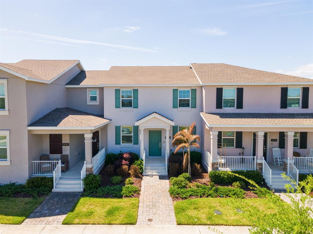 An exterior view of a multi-unit townhouse building with a central entrance and front porches — 1838 TOHOQUA BOULEVARD, KISSIMMEE, FL