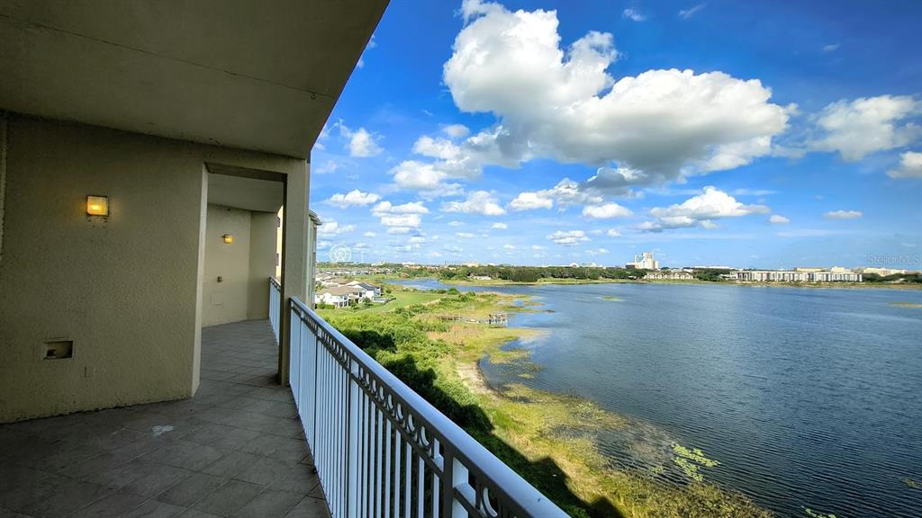 A balcony with a white railing overlooks a large lake and distant residential buildings — 8749 THE ESPLANADE UNIT 30, ORLANDO, FL