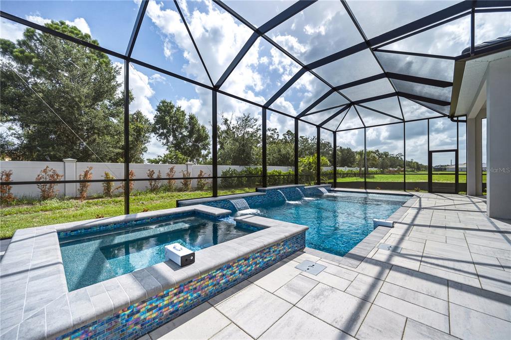 A screened-in patio features a tiled swimming pool and an elevated spa with water features — 17547 PALMISTE DRIVE, BRADENTON, FL