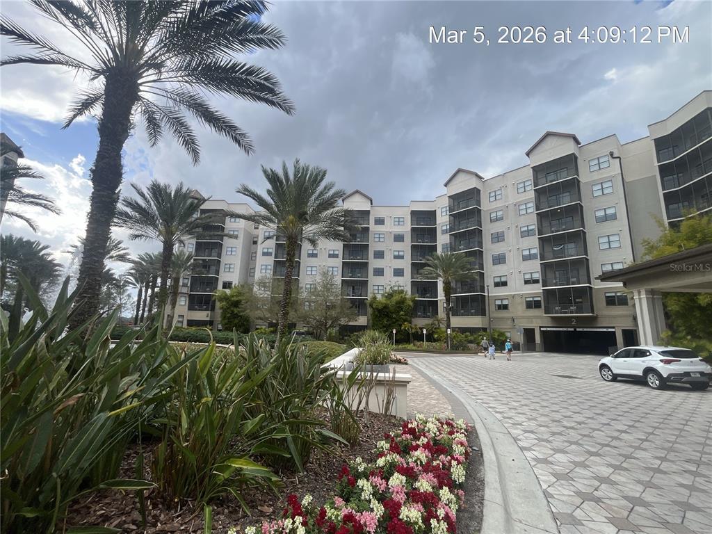 A multi-story apartment building with palm trees and a paved driveway in the foreground — 14501 GROVE RESORT AVENUE UNIT 1732, WINTER GARDEN, FL