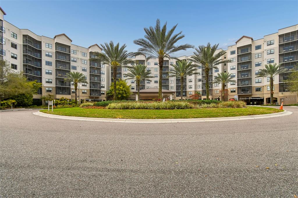 A multi-story apartment building with a circular driveway and palm trees in the foreground — 14501 GROVE RESORT AVENUE UNIT 1732, WINTER GARDEN, FL