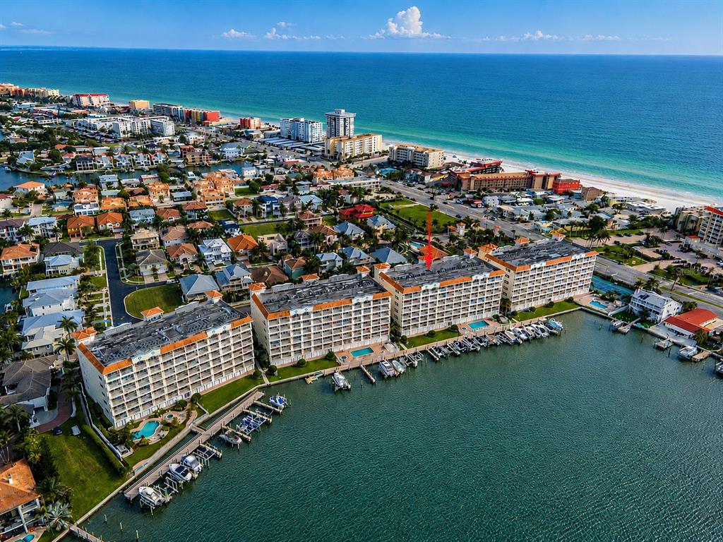 An elevated view shows a swimming pool, a boat dock with several vessels, and a bay — 17717 GULF BOULEVARD UNIT 504, REDINGTON SHORES, FL