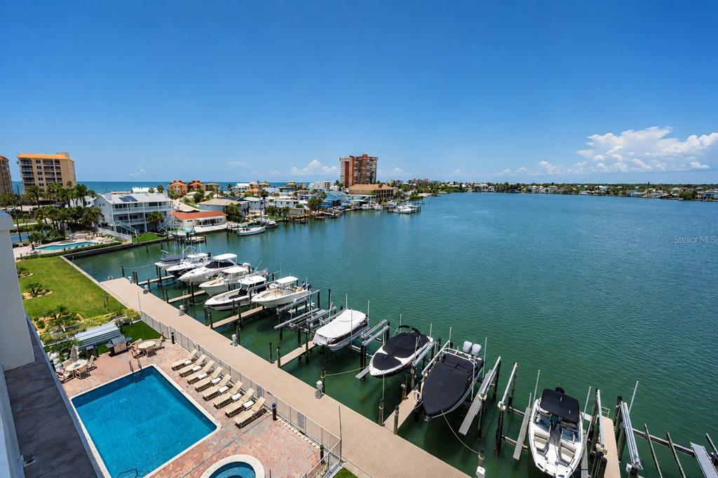 A spacious covered balcony with tile flooring overlooks a marina and a coastal waterway — 17717 GULF BOULEVARD UNIT 504, REDINGTON SHORES, FL