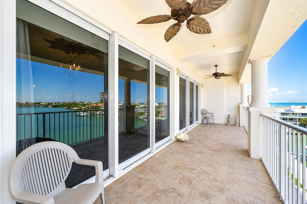 A tiled balcony features ceiling fans, sliding glass doors, and a view of the water — 17717 GULF BOULEVARD UNIT 504, REDINGTON SHORES, FL