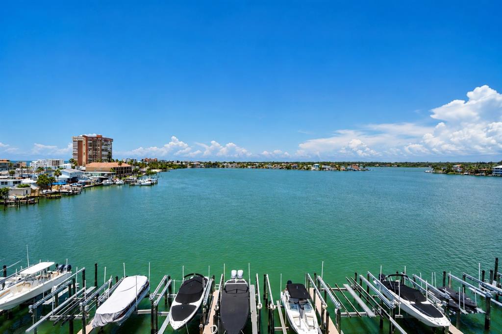 A tiled balcony overlooks a wide waterway with boat slips and distant waterfront homes — 17717 GULF BOULEVARD UNIT 504, REDINGTON SHORES, FL