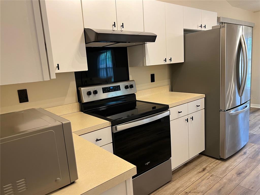 A kitchen features white cabinets, stainless steel appliances, and light-colored countertops — 6845 SW 81ST STREET, GAINESVILLE, FL