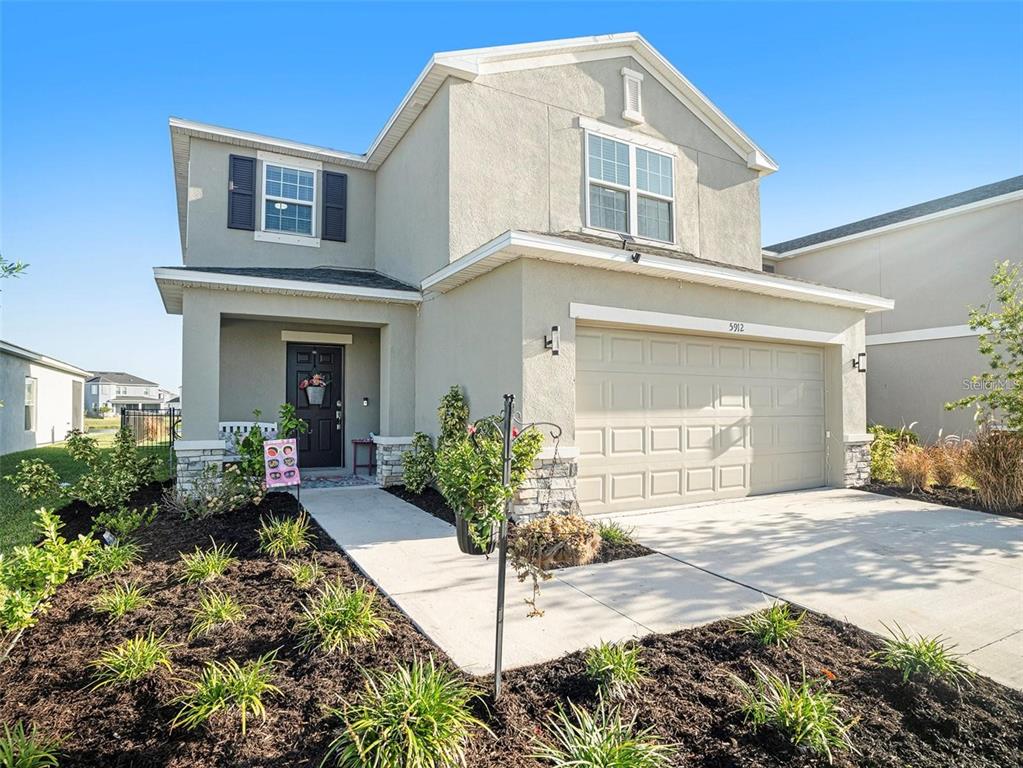A two-story suburban house with a beige stucco exterior, a two-car garage, and landscaping — 5912 LAURELCREST GLEN, PALMETTO, FL