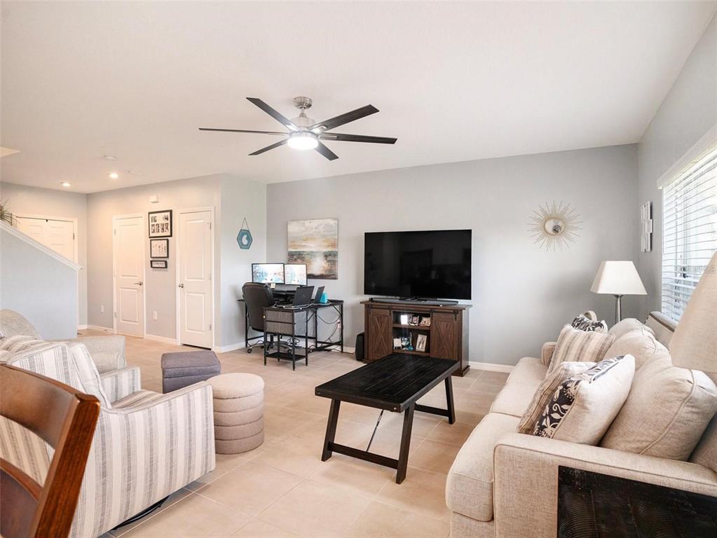 A living room features a television on a media console, a desk, and neutral furniture — 5912 LAURELCREST GLEN, PALMETTO, FL