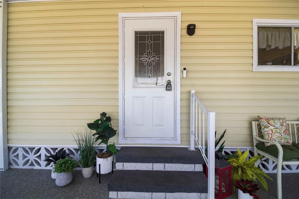 A white front door with a decorative glass insert is centered on a yellow-sided exterior — 2107 PALMA SOLA BOULEVARD UNIT 10, BRADENTON, FL
