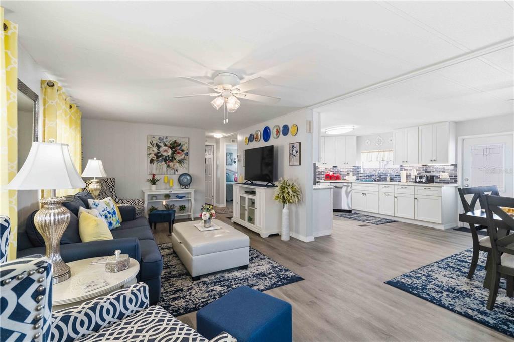 An open-concept living room and kitchen featuring white cabinetry, wood-look flooring, and blue accents — 2107 PALMA SOLA BOULEVARD UNIT 10, BRADENTON, FL