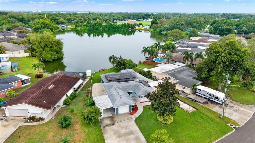 An aerial view shows two suburban houses with solar panels situated next to a lake — 5995 BLOSSOM LAKE DRIVE, SEMINOLE, FL