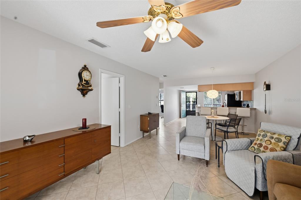 A living room with tile floors, a ceiling fan, and an open kitchen area — 7845 EAGLE CREEK DRIVE, SARASOTA, FL