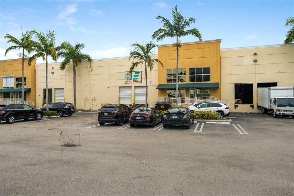 An exterior view of a commercial warehouse building with palm trees and a parking lot — 3530 NW 115th Avenue # 3530, Doral FL 33178, DORAL, FL