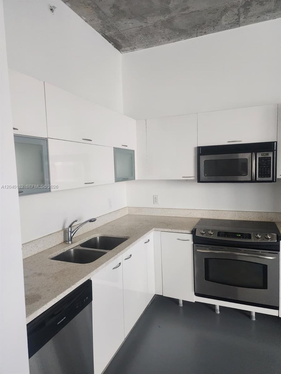 A kitchen features white flat-panel cabinets, stainless steel appliances, and a speckled countertop — 133 NE 2nd Ave # 904, Miami FL 33132, MIAMI, FL