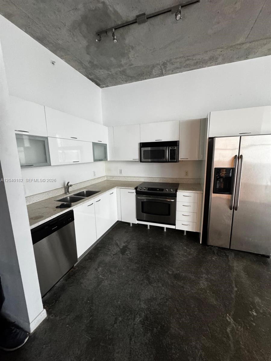 This kitchen features white cabinets, stainless steel appliances, and an exposed concrete ceiling — 133 NE 2nd Ave # 904, Miami FL 33132, MIAMI, FL