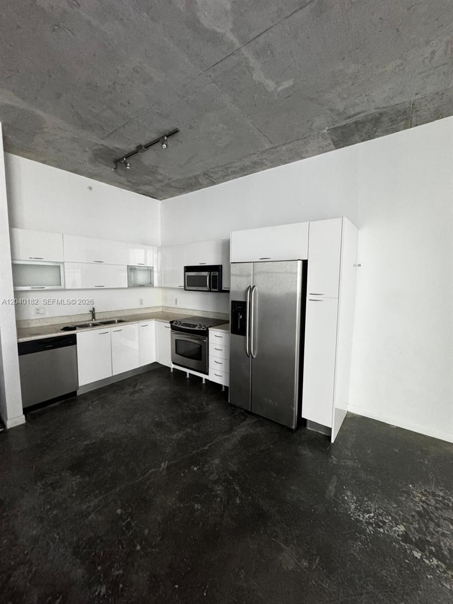 A modern kitchen features white cabinets, stainless steel appliances, and a raw concrete ceiling — 133 NE 2nd Ave # 904, Miami FL 33132, MIAMI, FL