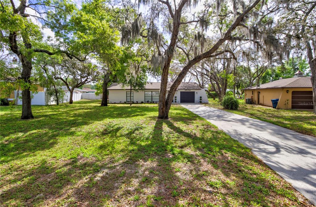 A single-story house with a driveway and large trees in the front yard — 198 TULSA AVENUE, SPRING HILL, FL