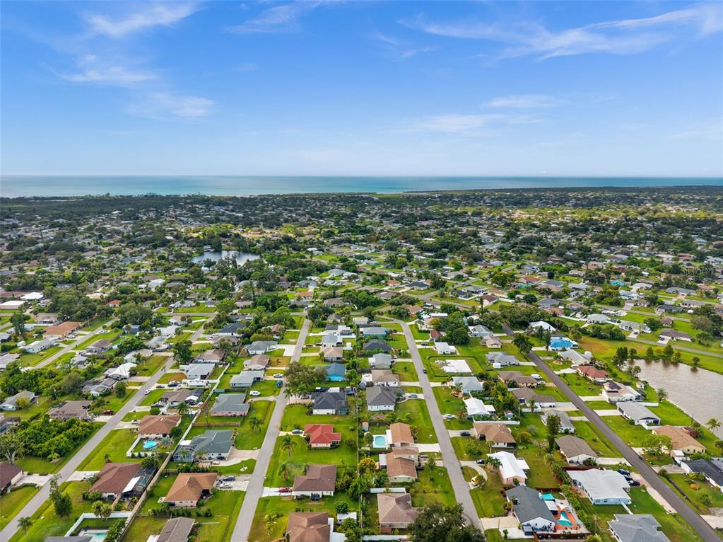 An aerial view shows a residential neighborhood with many houses and a distant coastline — 219 CORAL ROAD, VENICE, FL