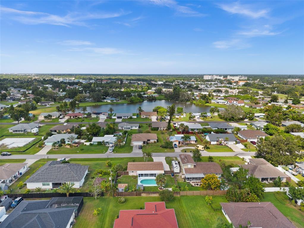 An aerial view shows a suburban neighborhood with houses, a central lake, and green lawns — 219 CORAL ROAD, VENICE, FL