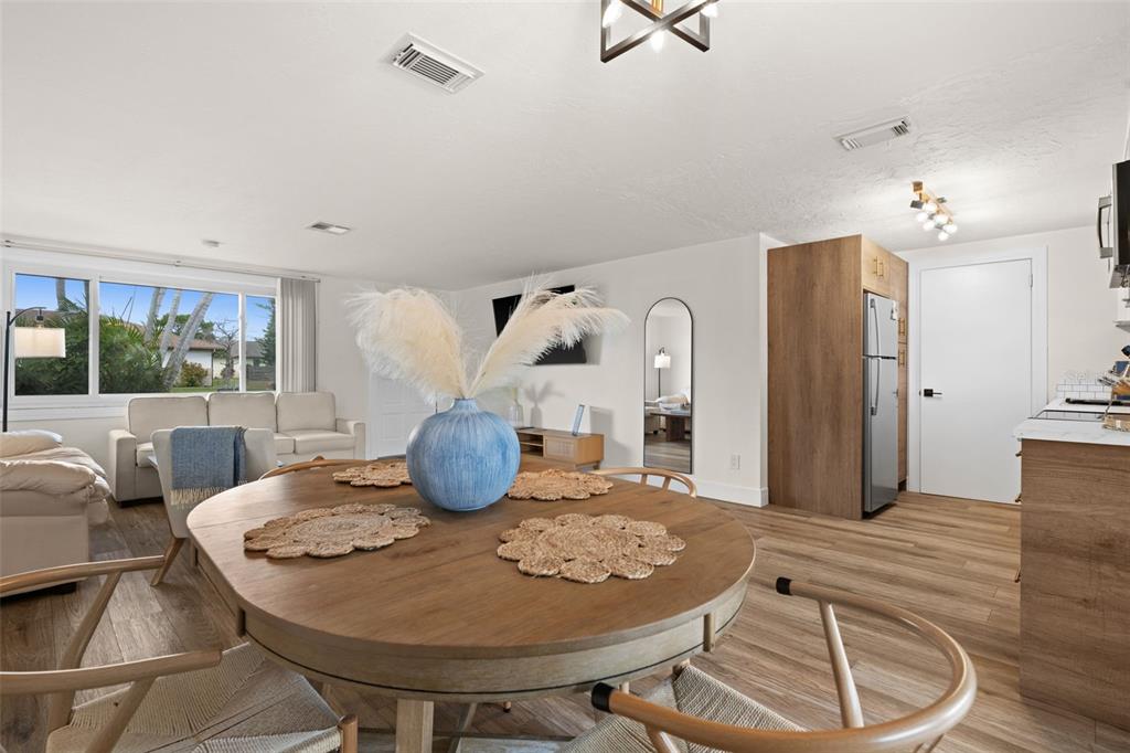 A dining area with a round wooden table sits in an open-concept living space — 219 CORAL ROAD, VENICE, FL