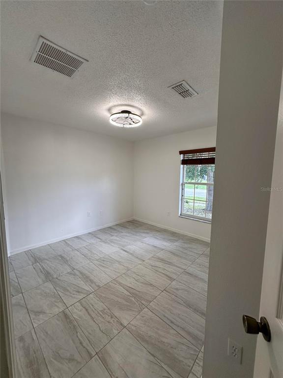 A bedroom with light-colored tile flooring, white walls, a ceiling fan, and a single window — 4502 PHILADELPHIA CIRCLE, KISSIMMEE, FL