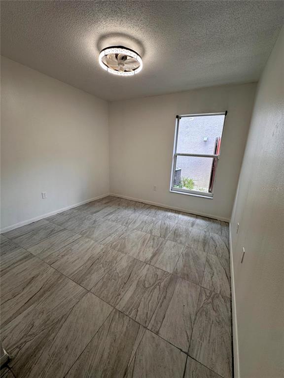 An empty room with light-colored tile flooring, white walls, and a ceiling fan light fixture — 4502 PHILADELPHIA CIRCLE, KISSIMMEE, FL