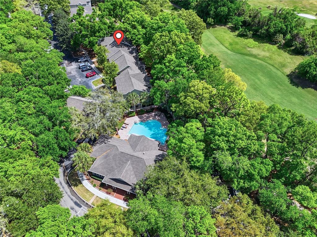 An aerial view shows a multi-unit building with a pool surrounded by dense trees — 10000 SW 52ND AVENUE UNIT B6, GAINESVILLE, FL
