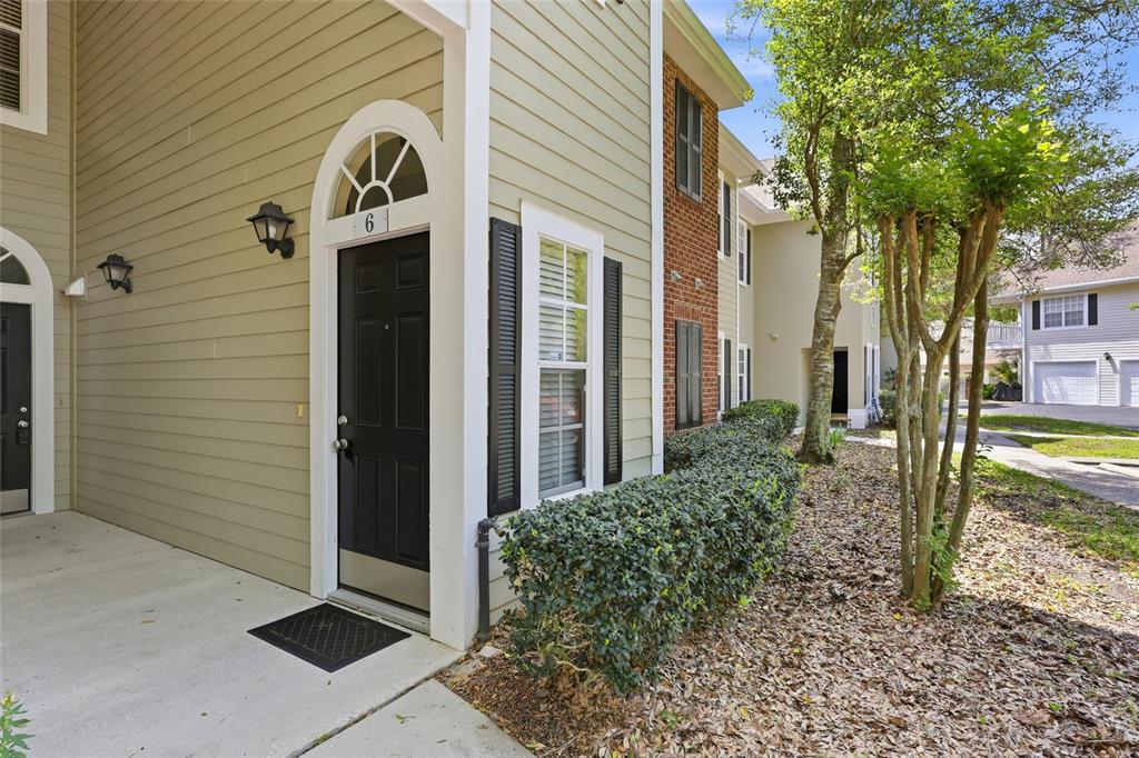 The exterior of a tan-sided building features a black front door with a number six — 10000 SW 52ND AVENUE UNIT B6, GAINESVILLE, FL