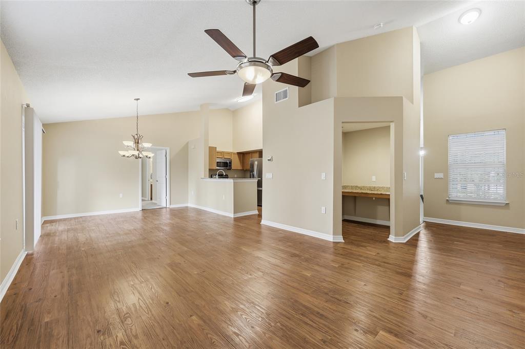 A spacious living area with wood-look flooring, a ceiling fan, and an open kitchen — 10000 SW 52ND AVENUE UNIT B6, GAINESVILLE, FL
