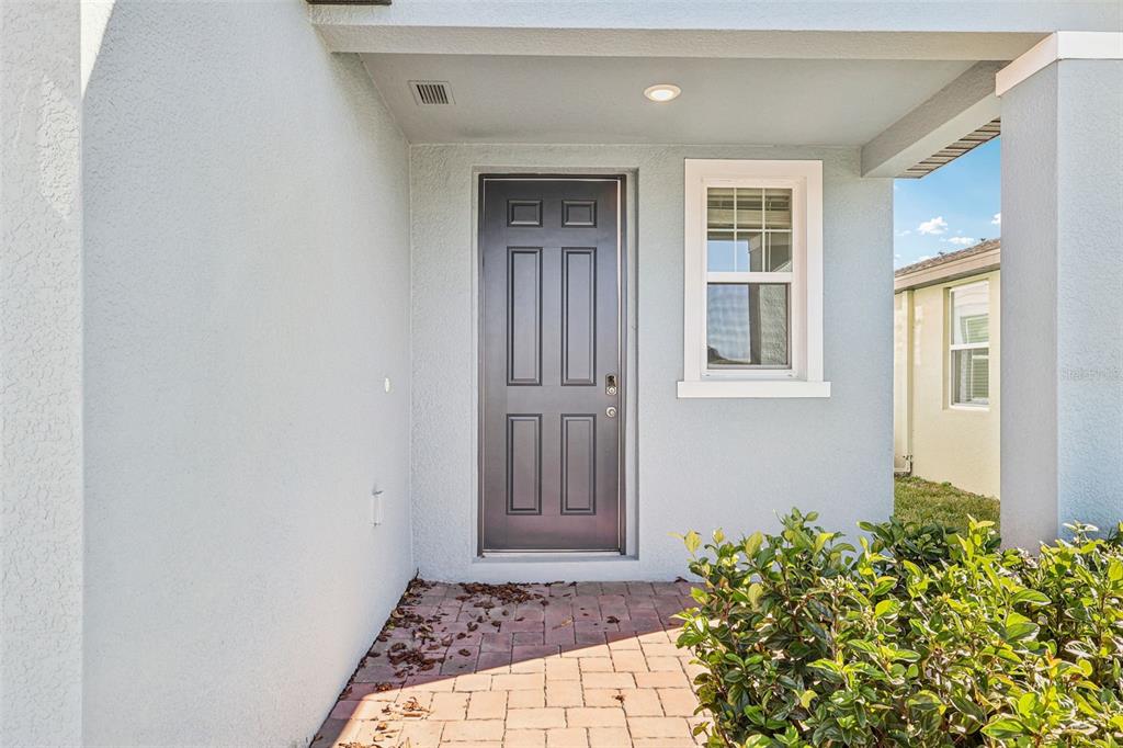 A front entryway features a dark gray door, a single window, and a paved walkway — 3793 BLUETHREAD WAY, POINCIANA, FL
