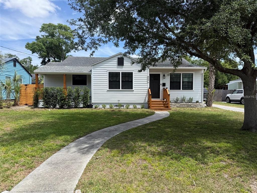 A white single-story house with a front walkway, wooden steps, and a large shade tree — 6007 N CENTRAL AVENUE, TAMPA, FL