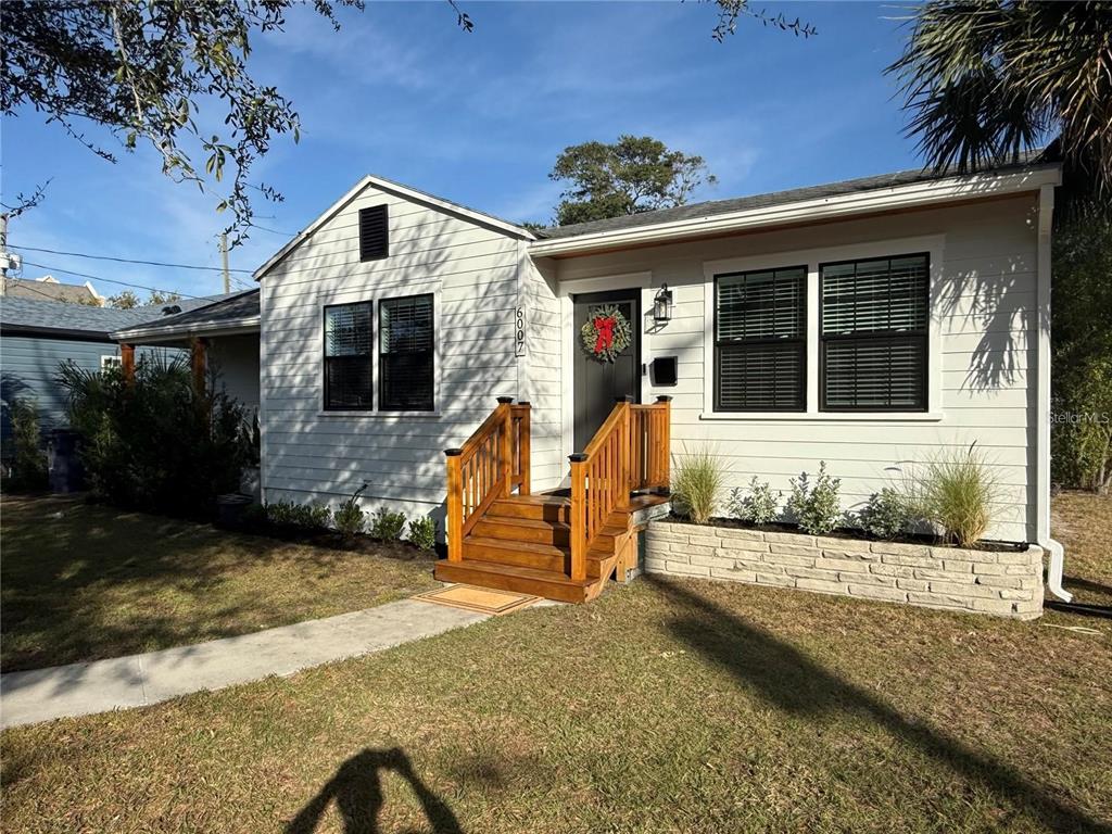 A single-story house with white siding, black window frames, and a wooden front porch — 6007 N CENTRAL AVENUE, TAMPA, FL