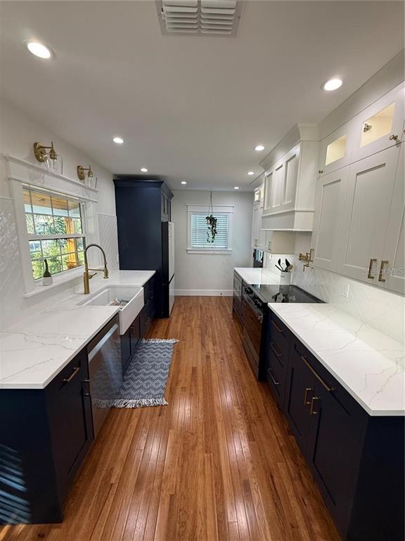 A galley kitchen features dark blue lower cabinets, white upper cabinets, and white quartz countertops — 6007 N CENTRAL AVENUE, TAMPA, FL
