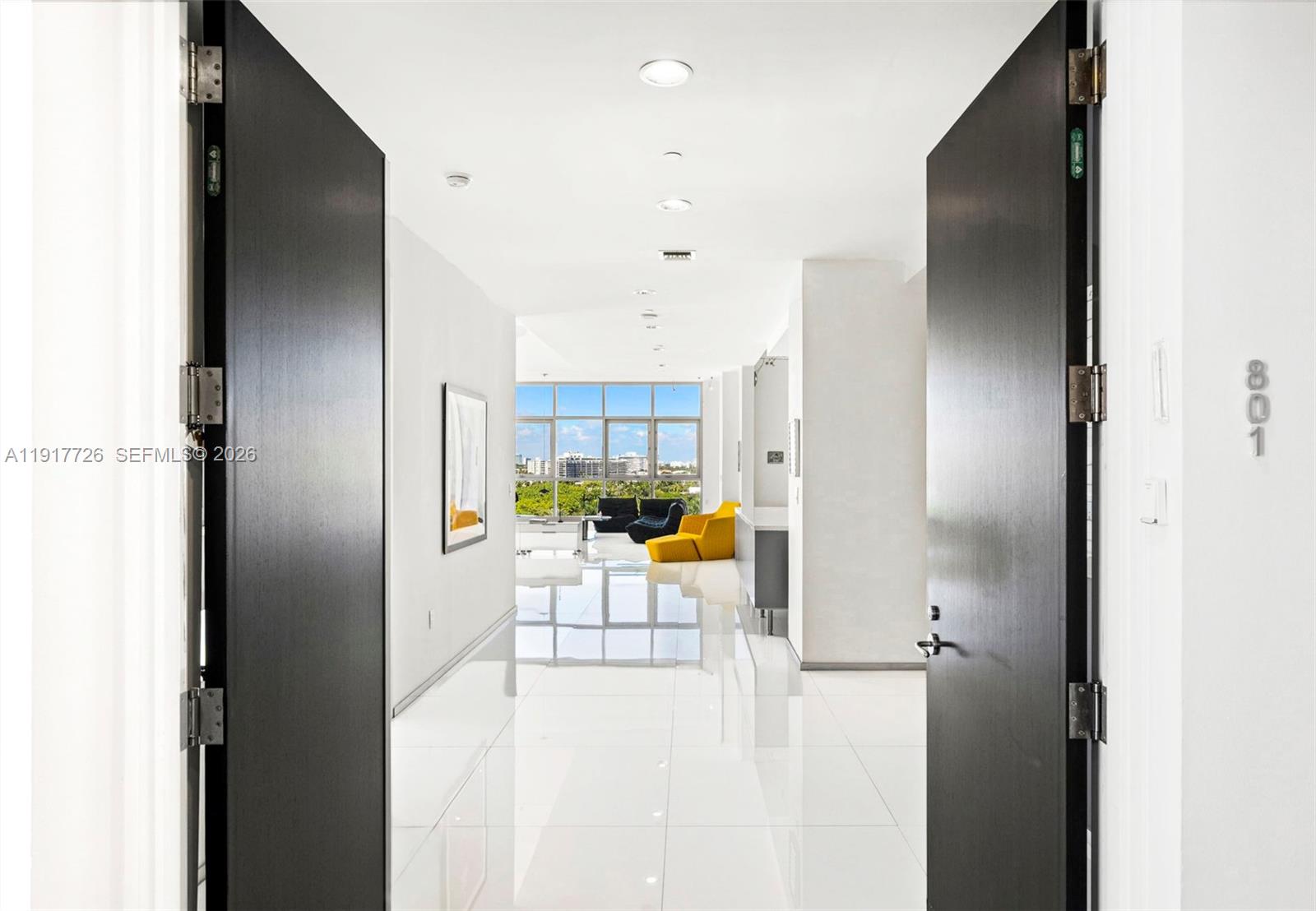 A bright, white-tiled hallway leads to a living area with floor-to-ceiling windows and furniture — 201 Aqua Ave # 801, Miami Beach FL 33141, MIAMI BEACH, FL