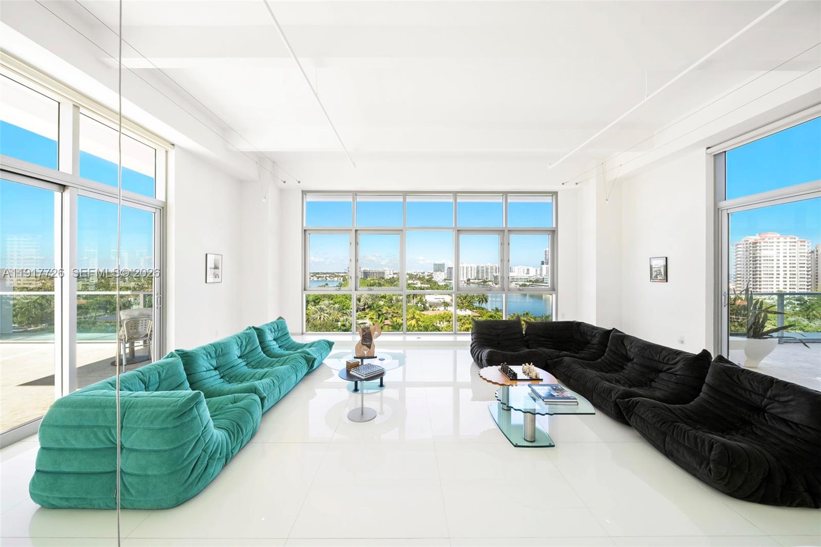 A bright living room features white tile floors, floor-to-ceiling windows, and two large modular sofas — 201 Aqua Ave # 801, Miami Beach FL 33141, MIAMI BEACH, FL