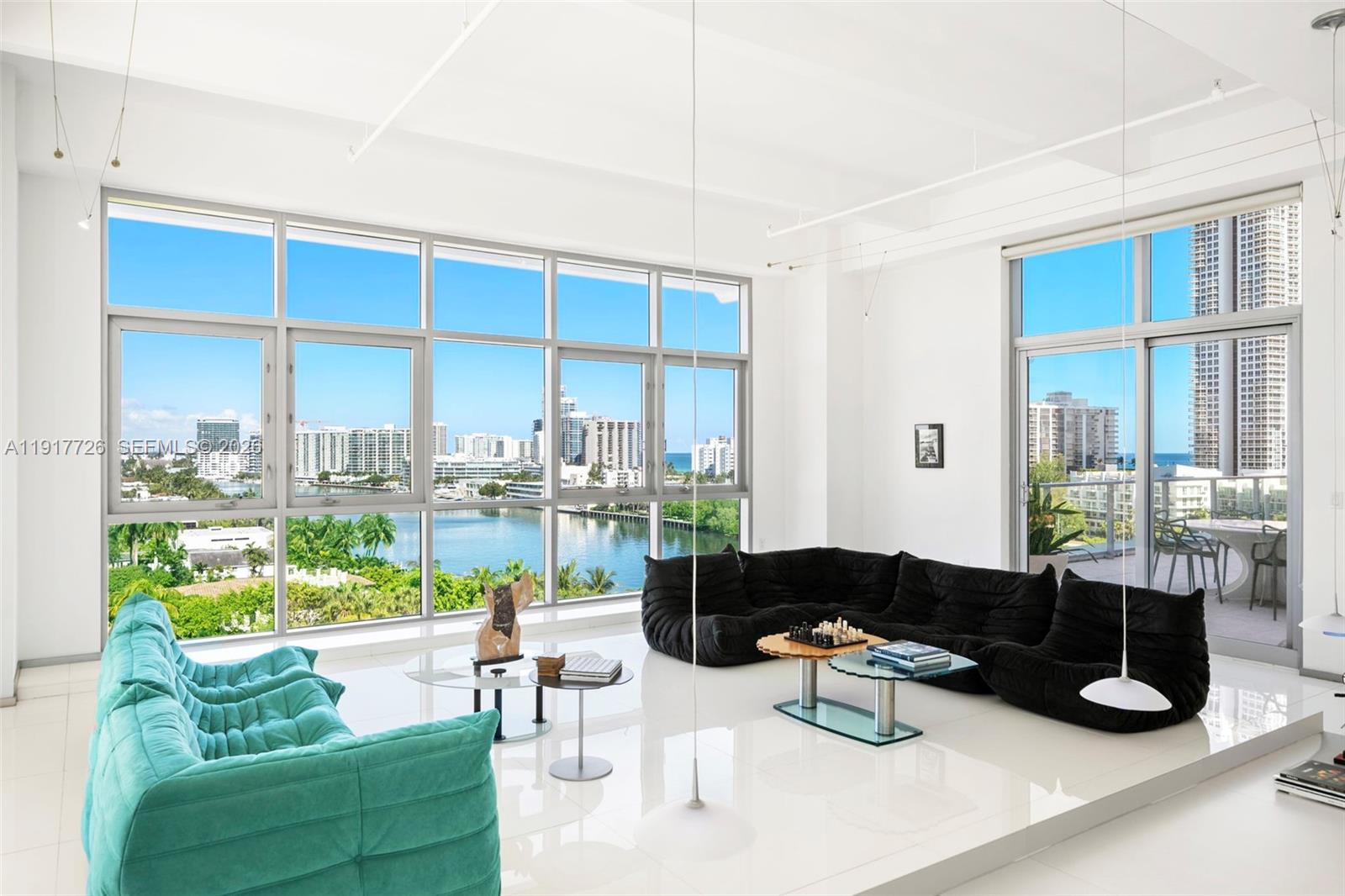 A bright living room features white floors, floor-to-ceiling windows, and two modern modular sofas — 201 Aqua Ave # 801, Miami Beach FL 33141, MIAMI BEACH, FL