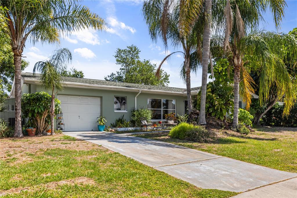 A single-story house with a light green exterior, a garage, and several palm trees — 1508 ERIN LANE, CLEARWATER, FL
